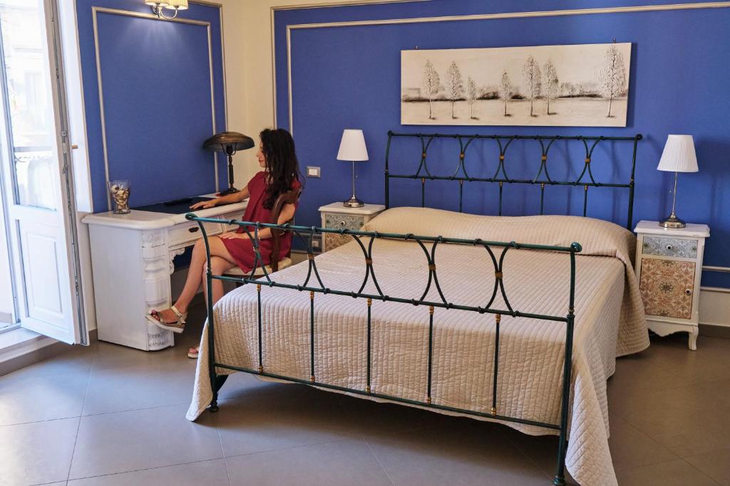 a woman sitting at a desk in a bedroom at B&B San Trifone in Adelfia