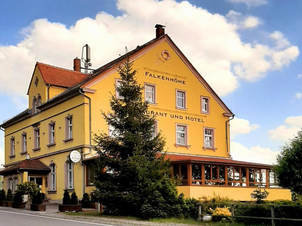 un edificio amarillo con un reloj a un lado en Restaurant & Hotel Zur Falkenhöhe en Falkenau