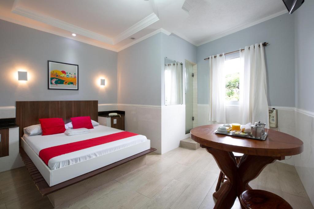 Un dormitorio con una cama con almohadas rojas y una mesa de madera. en Hotel Anália Franco, en São Paulo