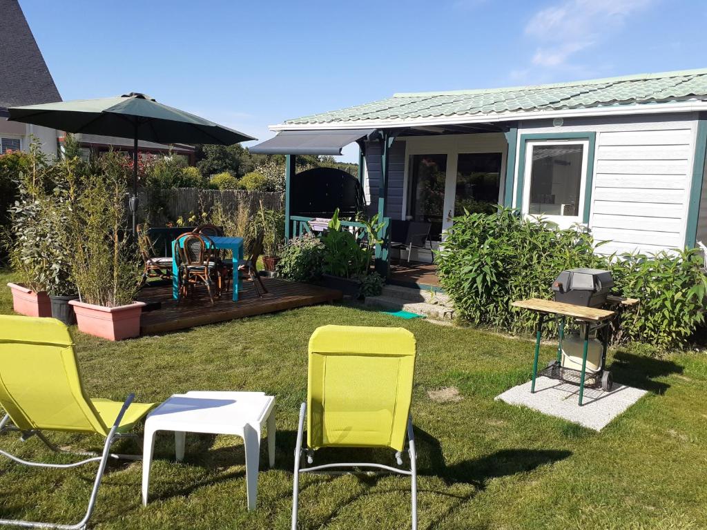 een groep stoelen en tafels in een tuin bij Petite Maison Chalet à 100 m de la petite mer de Gâvres in Riantec