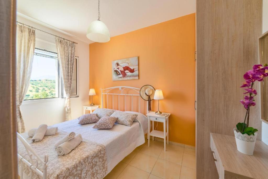 1 dormitorio con 1 cama con paredes de color naranja y ventana en Villa George Sea View with pool - Triopetra en Triopetra