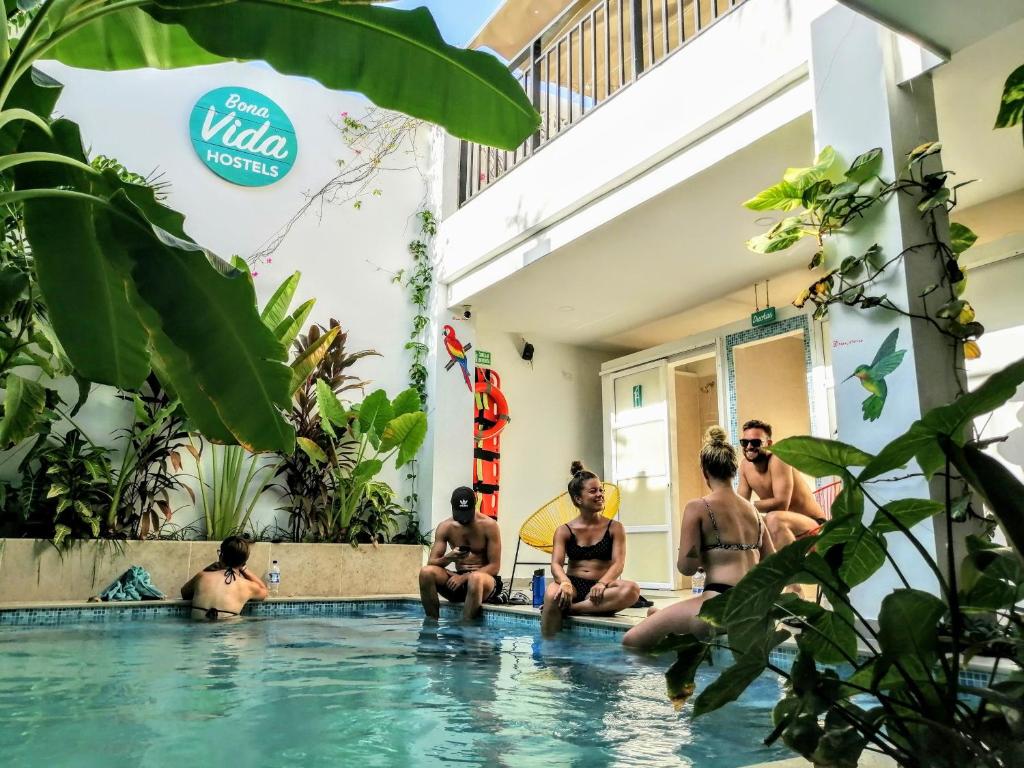 a group of men sitting in a swimming pool at Bona Vida Hostel in Ríohacha