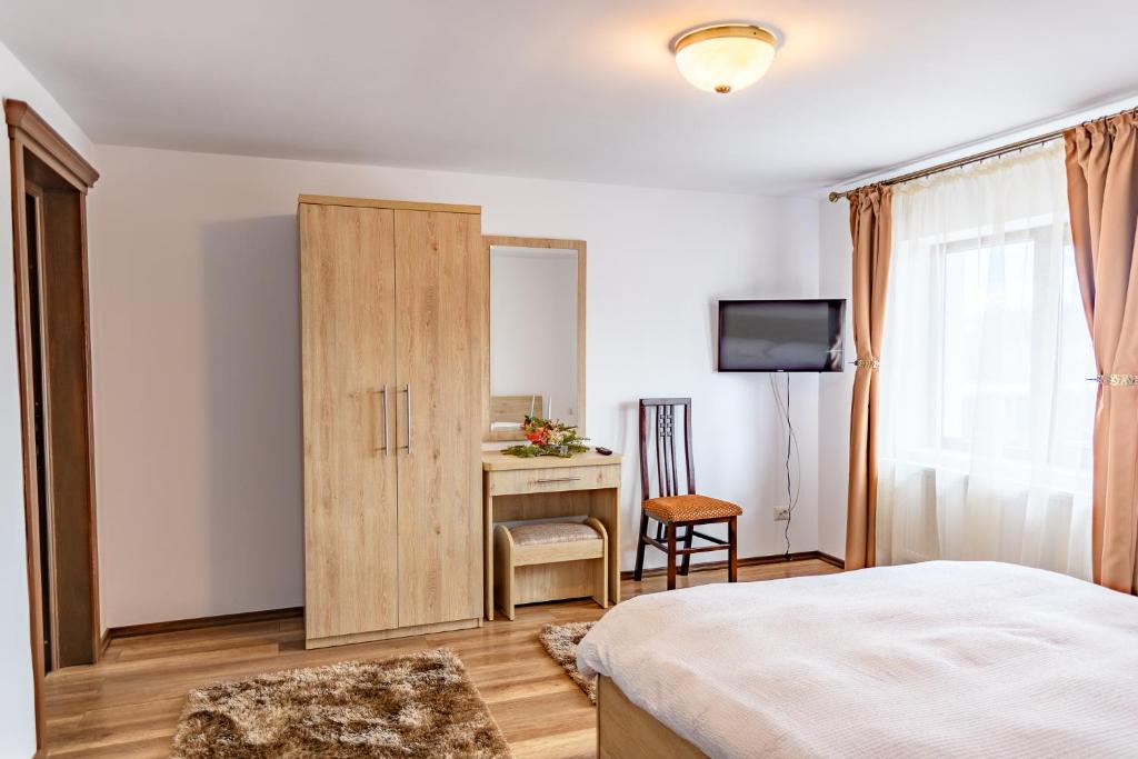 a bedroom with a bed and a cabinet and a desk at Cabana Nemtisor in Nemţişor