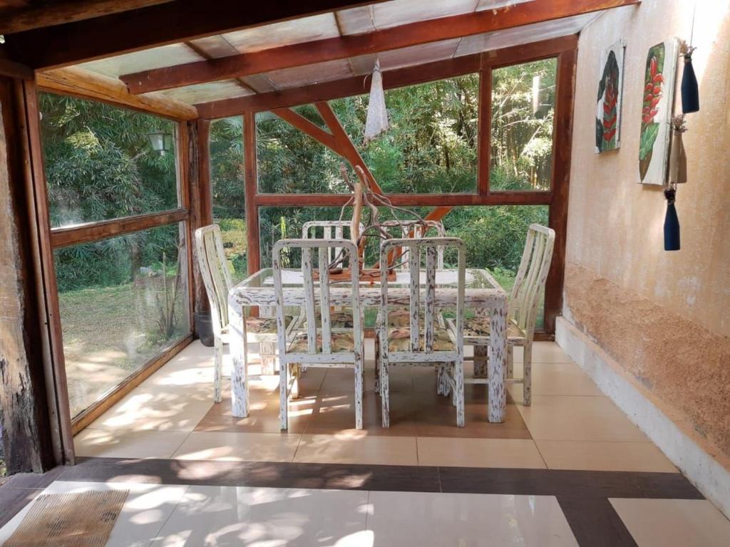 a dining room with a table and chairs and windows at SITIO RUSTICO BEIRA RIO in Guararema