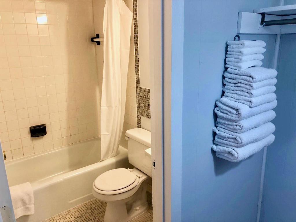 a bathroom with a toilet and a tub and a pile of towels at Rideau Oceanfront Motel in Ocean City