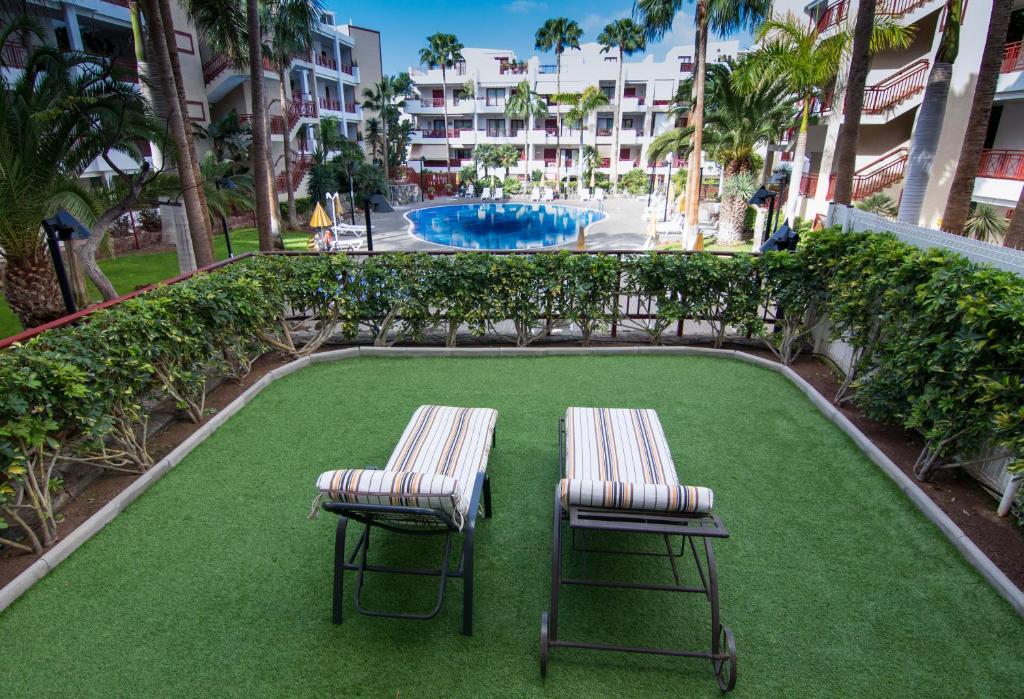 two chairs and a swimming pool in a resort at Apartamento Los Balandros in Palm-mar