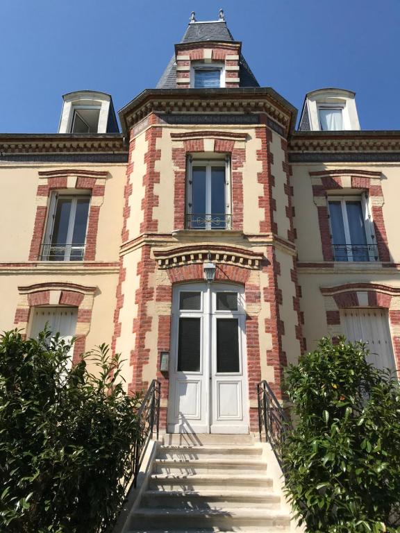 - un bâtiment avec des escaliers menant à une porte dans l'établissement Villa saint Louis 3, à Cabourg