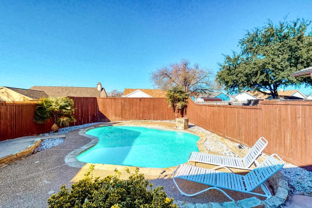 a swimming pool with two chairs and a fence at Fun Times in the Colony in The Colony