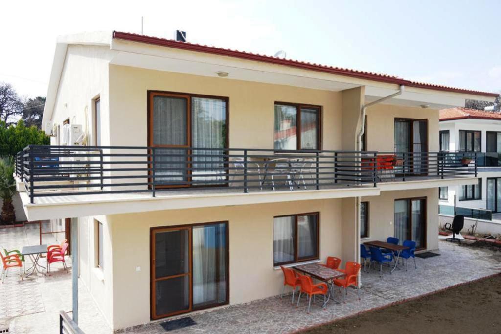 uma casa com uma varanda com cadeiras e mesas em Ören Konak Apart Otel em Burhaniye