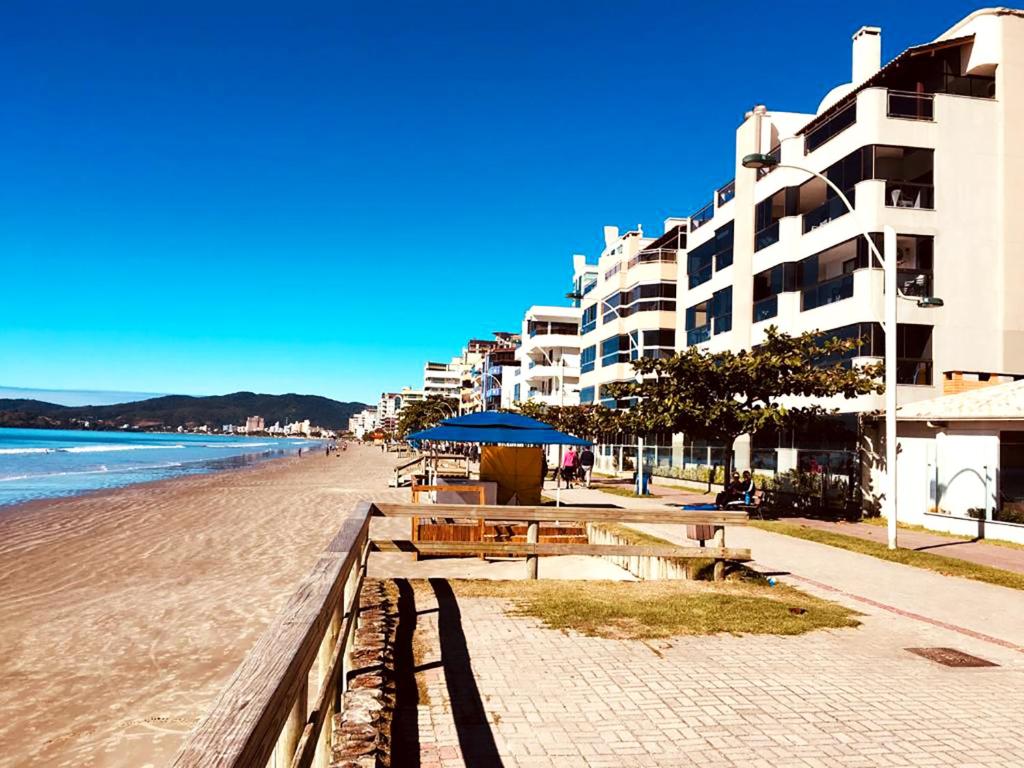 una playa con mesas y sombrilla y algunos edificios en Apto a beira mar com churrasq privativa em Itapema, en Meia Praia