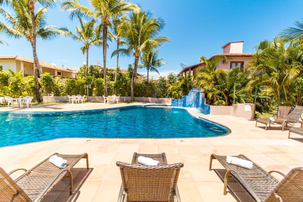 - une piscine bordée de chaises et de palmiers dans l'établissement Novo Sol Hotel - Rede Soberano, à Porto Seguro