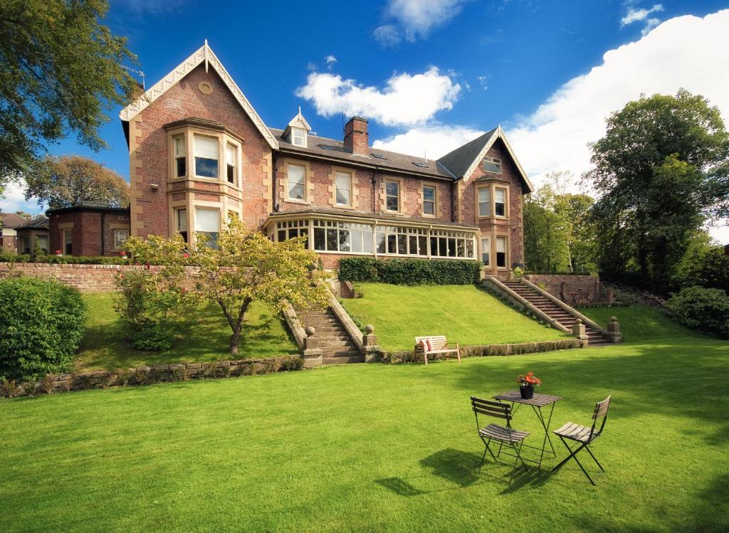 una gran casa de ladrillo con 2 sillas en el césped en Eslington Villa en Gateshead