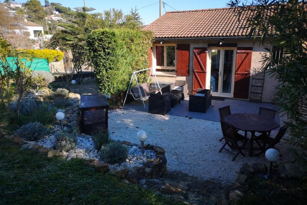 a backyard with a table and chairs and a house at Jolie petite Maison de Charme dans quartier boisé in Vallauris