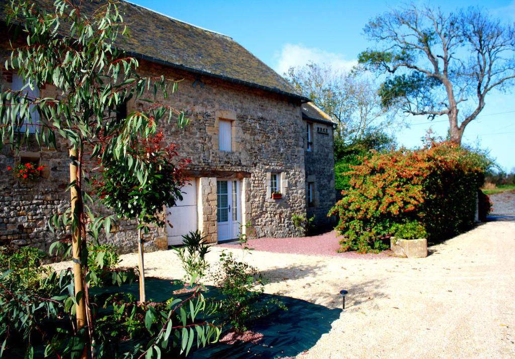 an old stone house with a white door at Maison 2 chambres avec espace extérieur privé et petit-déjeuner en supplément - fait-maison et produits locaux in Vierville-sur-Mer