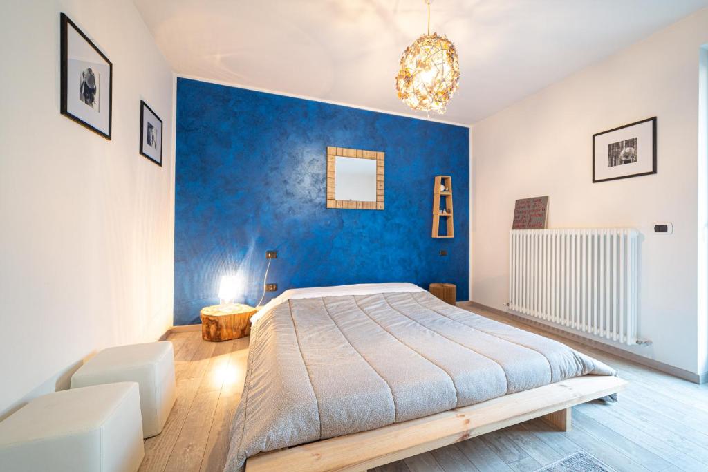 - une chambre avec un grand lit et un mur bleu dans l'établissement La Tana del Coniglio, Comano Terme Holiday, à Comano Terme
