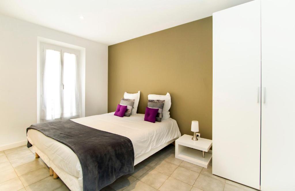 een slaapkamer met een groot bed met paarse kussens bij Florella Achard Apartment in Cannes