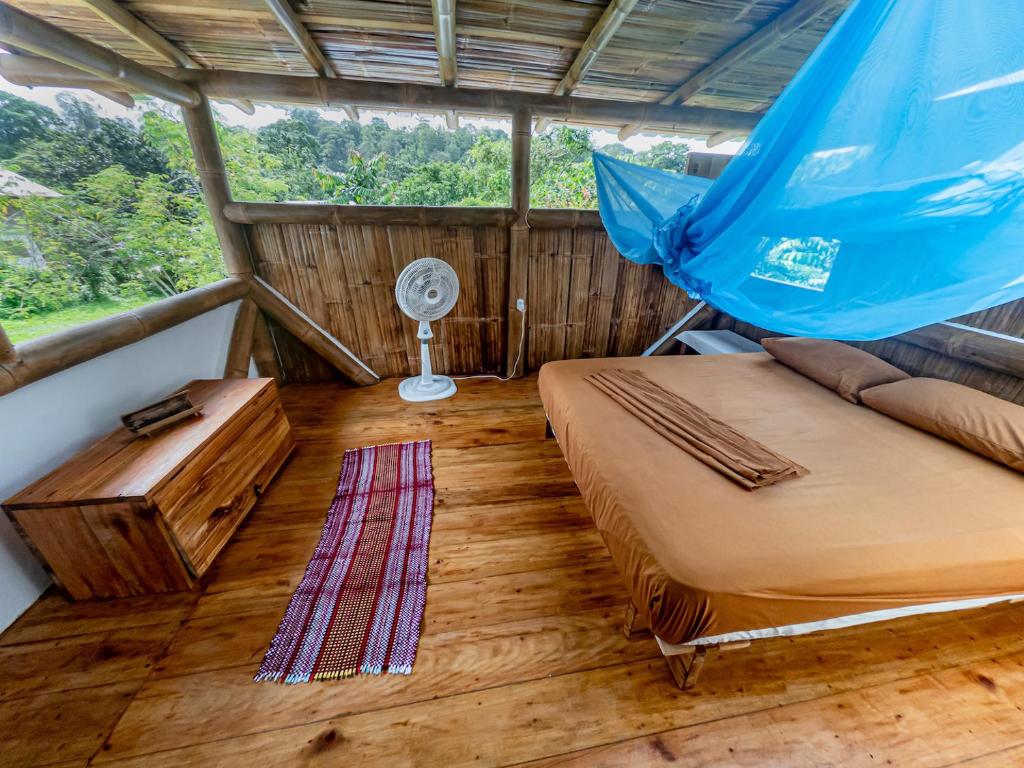 Habitación con 2 camas, mesa y ventilador. en Maracumbo Lodge en Mompiche