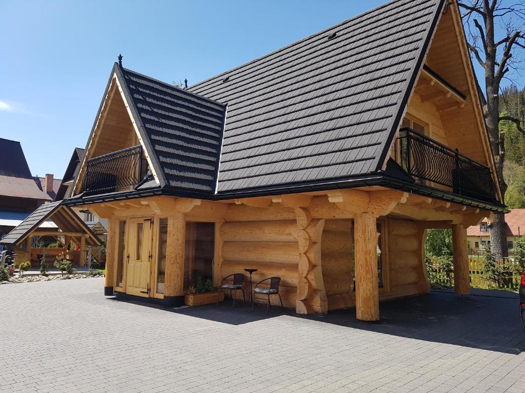 a large log cabin with a black roof at Tatrzańskie Domki in Poronin
