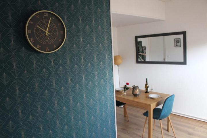 a clock on a wall next to a table with a chair at Studio de charme en plein centre ville in Beauvais