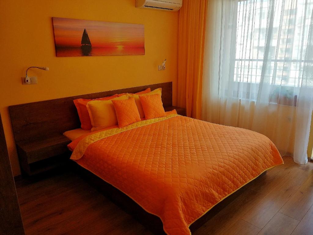 a bedroom with a bed with orange sheets and a window at Sunny in Burgas City