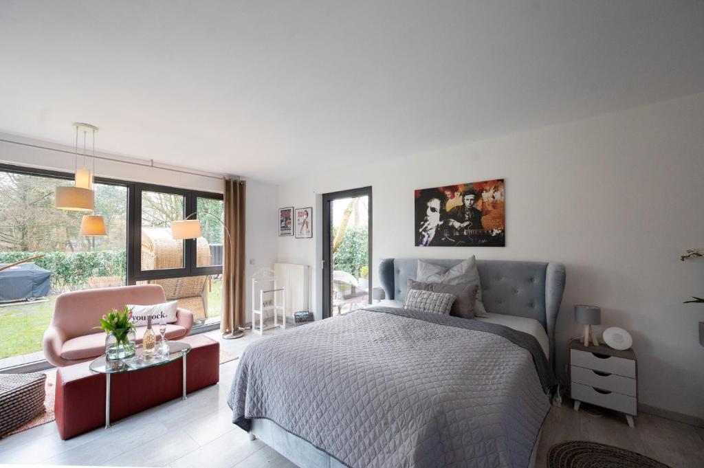 a white bedroom with a bed and a chair at RockLoft Oldenburg in Oldenburg