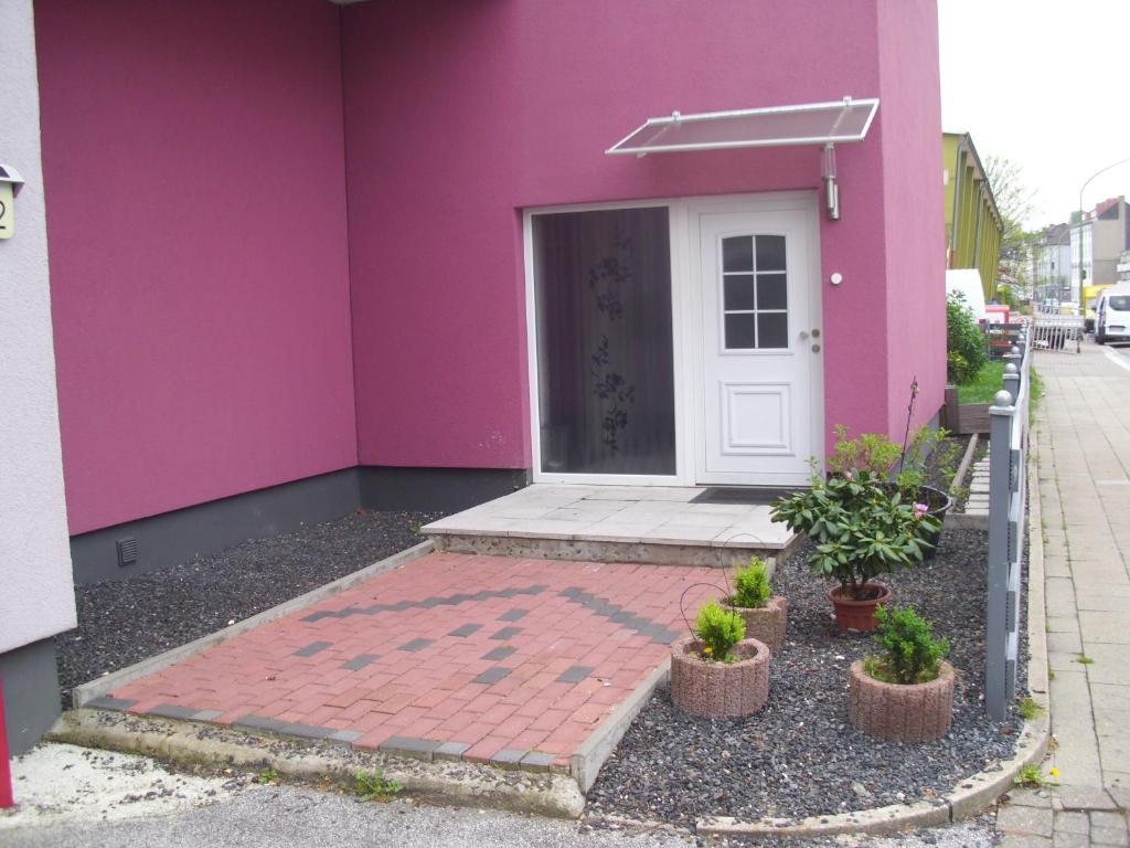 um edifício cor-de-rosa com uma porta branca e vasos de plantas em Casa Rose em Essen