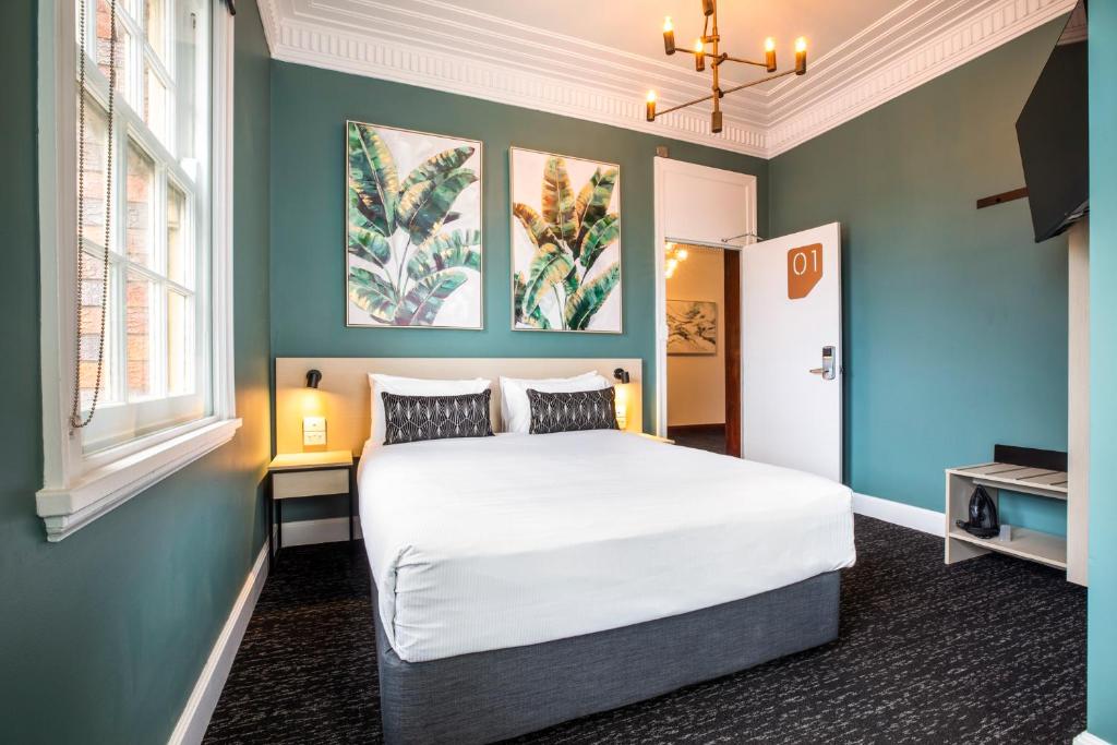 a bedroom with a large bed with blue walls at Nightcap at Pymble Hotel in Pymble