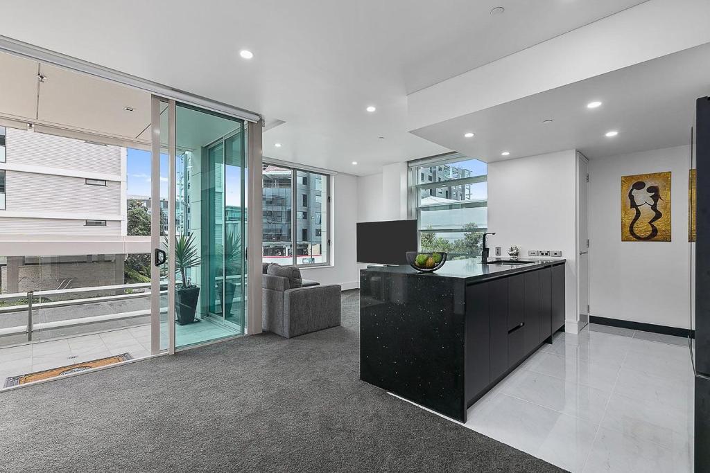 eine Küche mit einer schwarzen Insel im Wohnzimmer in der Unterkunft QV Stays Upscale Modern Viaduct Haven in Auckland