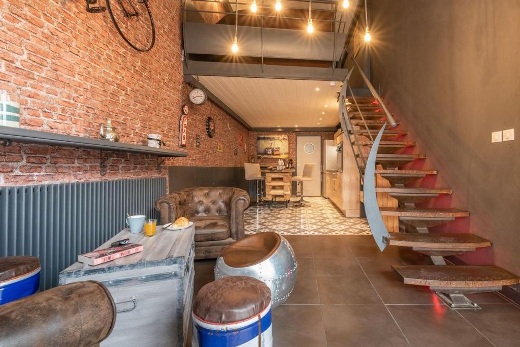 - un salon avec un escalier et un mur en briques dans l'établissement Loft industriel en centre ville, au Puy-en-Velay