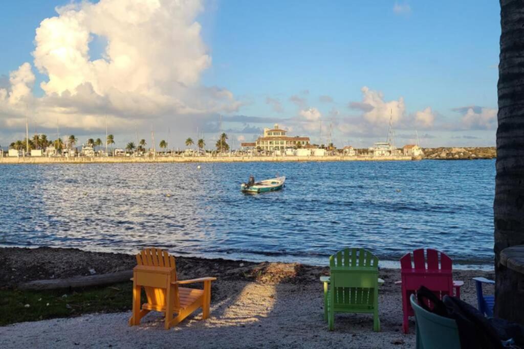 a group of chairs on the beach with a boat in the water at Simple Hollywood Beach in Humacao