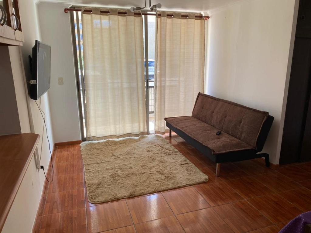 a living room with a couch and a large window at Departamento amoblado por día in Arica
