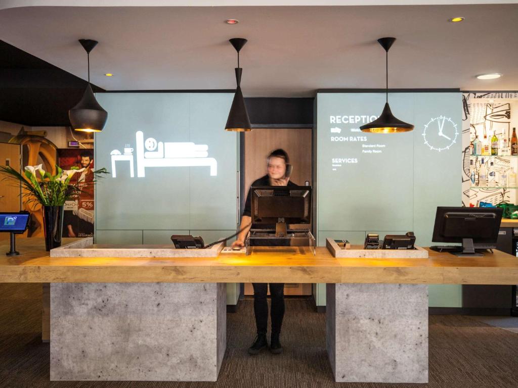 a man standing behind a counter in a store at ibis London Barking in Barking