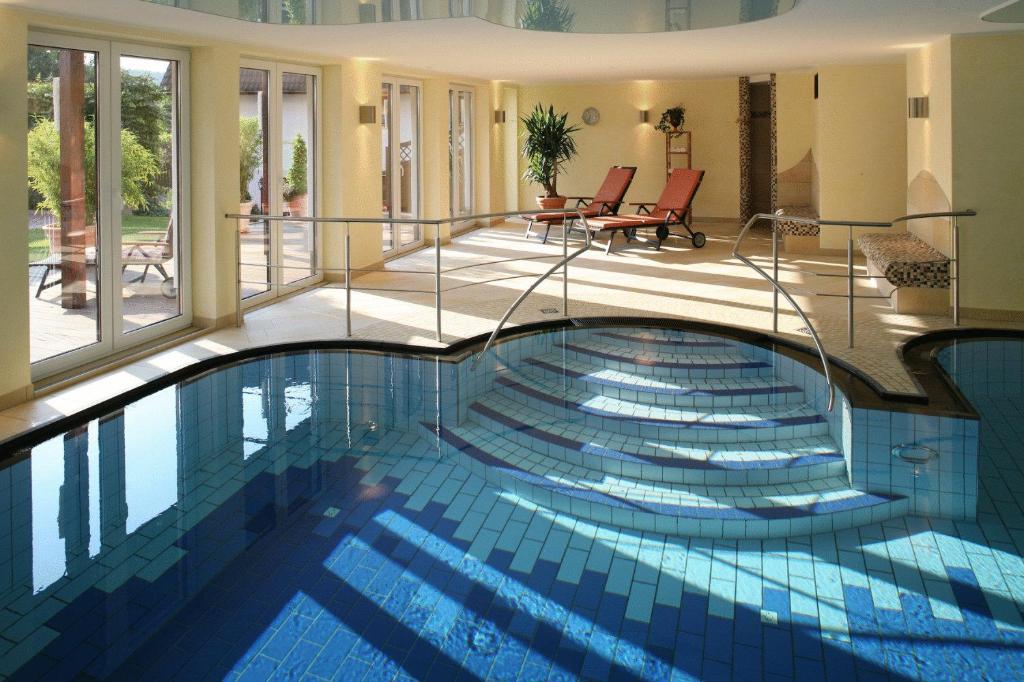 a swimming pool in a house with glass walls at Landhotel Teuteberg in Bad Arolsen