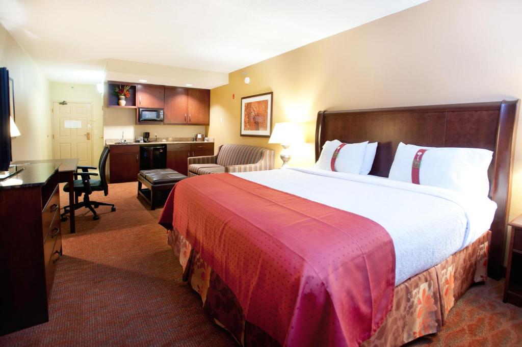 a hotel room with a large bed and a kitchen at Holiday Inn Hotel & Suites Council Bluffs, an IHG Hotel in Council Bluffs