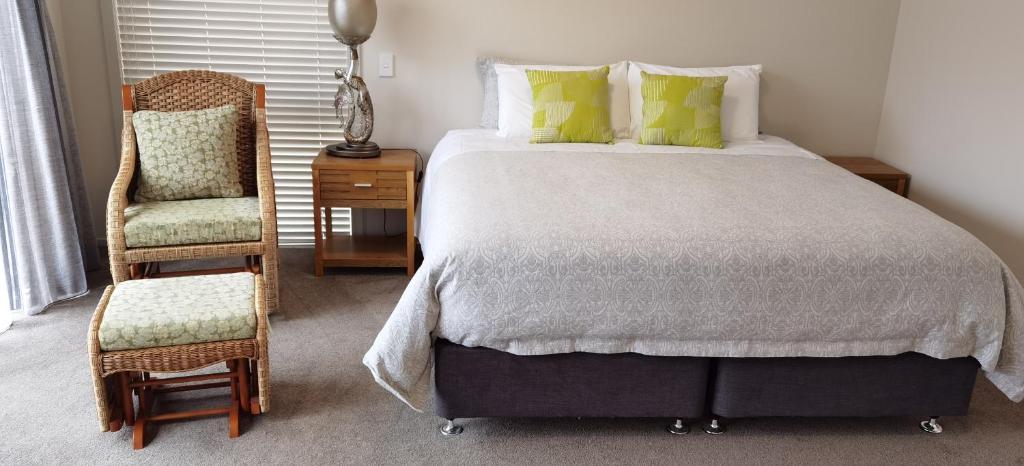 a bedroom with a large bed and a chair at Road Sun Tourist Lodge in Dunedin