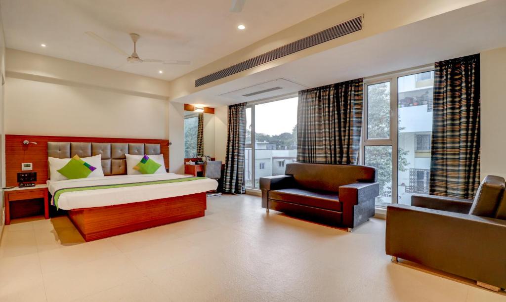 a bedroom with a bed and a couch and a chair at Treebo Trend Ranjeet Shivaji Nagar in Pune
