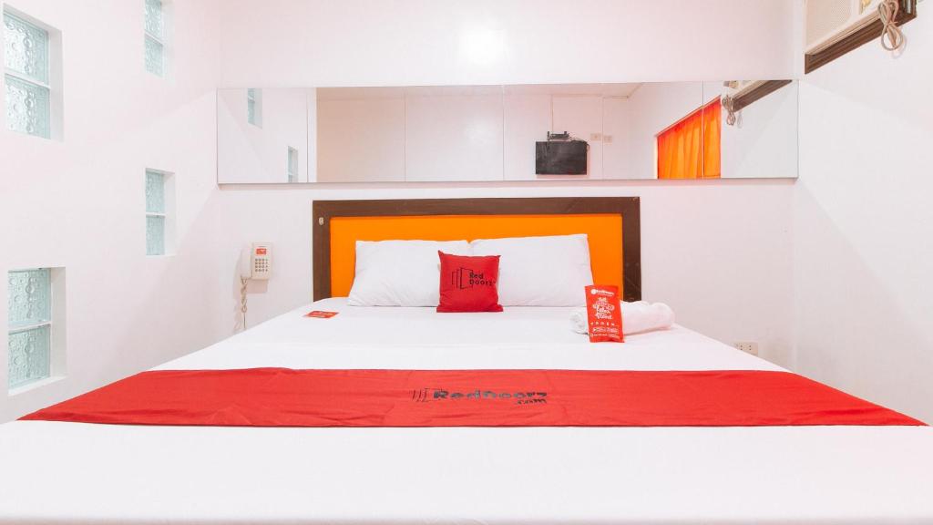 een slaapkamer met een groot wit bed met rode kussens bij RedDoorz @ EL Runway Hotel Bulacan in Bulacan