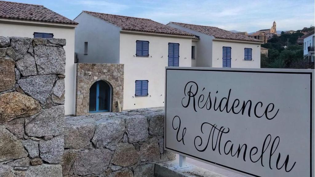 un panneau devant un mur avec une maison dans l'établissement Résidence U Manellu, à Santa-Reparata-di-Balagna