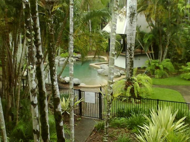 a swimming pool in a garden with trees at Reef Terraces on St Crispins in Port Douglas