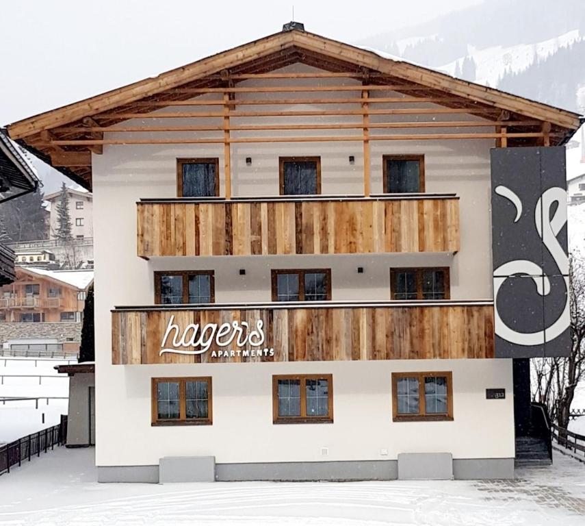 a building with a sign on it in the snow at hager's apartments in Saalbach Hinterglemm