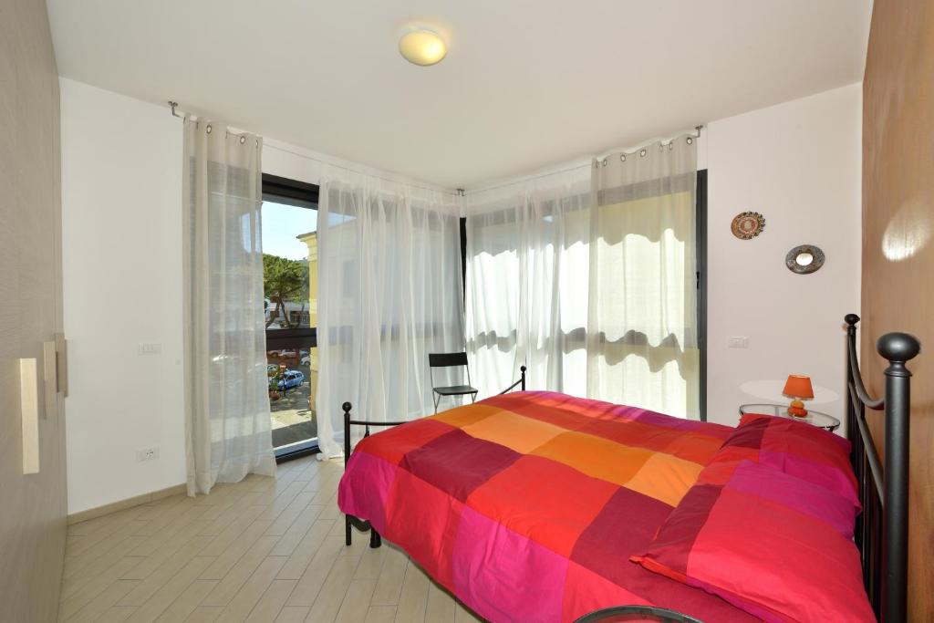 een slaapkamer met een kleurrijk bed en een groot raam bij Residenza Serenella in Diano Marina