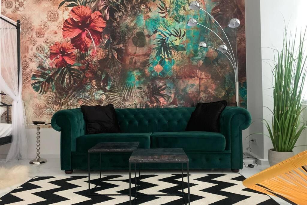 um sofá verde numa sala de estar com uma parede floral em COOL City CENTER Apt. @ METRO and SHOPPING STREET em Viena