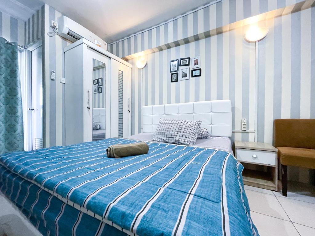 niebiesko-biała sypialnia z łóżkiem i krzesłem w obiekcie Green Bay Pluit Apartment - Seaview Studio Fast Wifi w Dżakarcie