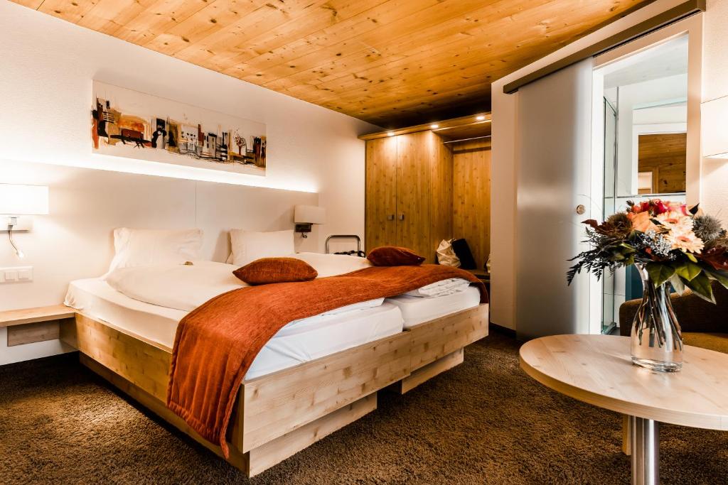 a bedroom with a large bed and a table at Lifestyle & Spa Hotel Grächerhof in Grächen