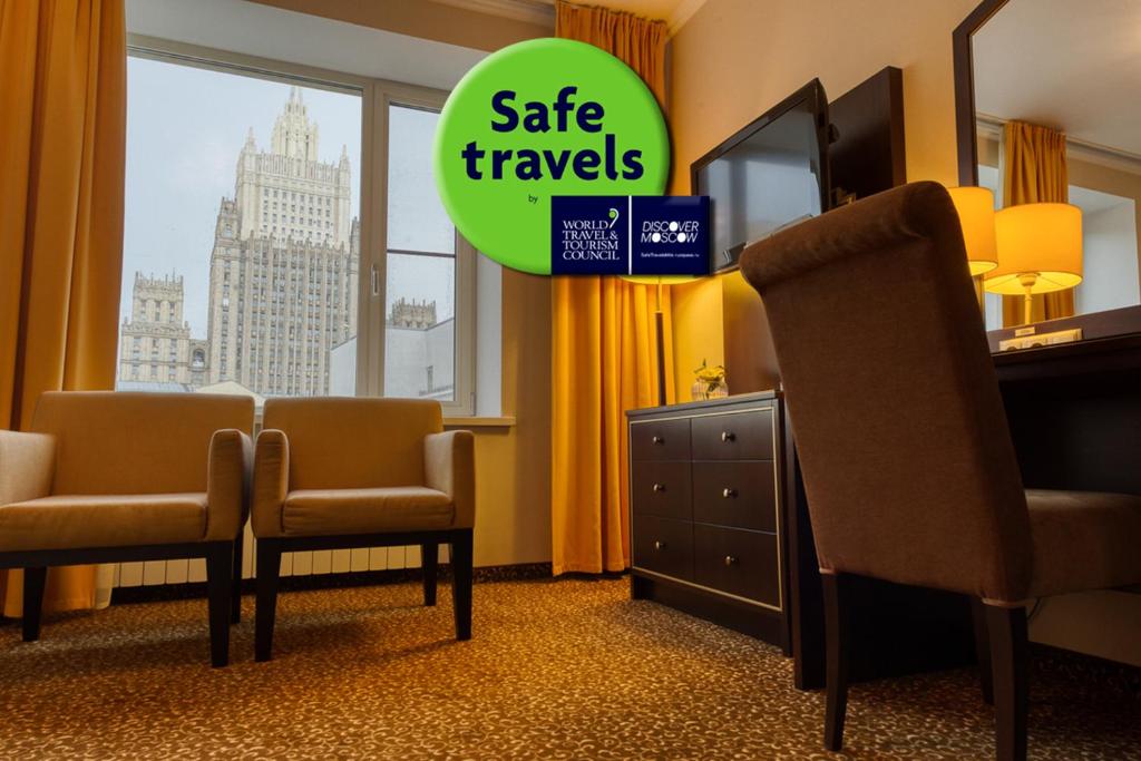 ein Hotelzimmer mit 2 Stühlen, einem TV und einem Fenster in der Unterkunft Arbat Hotel in Moskau