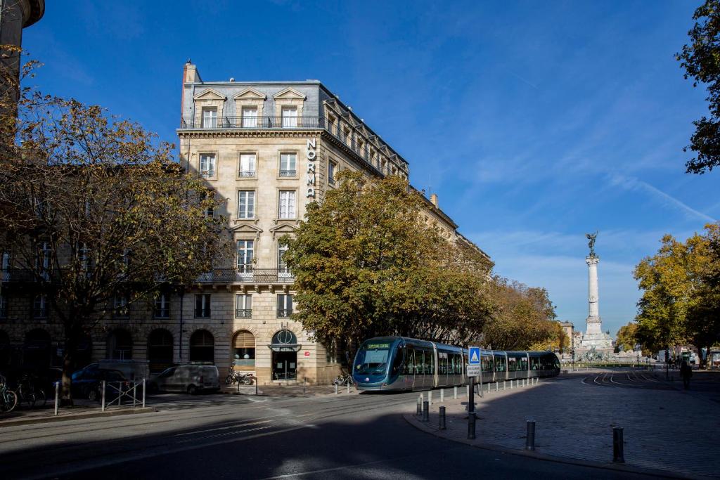 Niebieski autobus stoi przed budynkiem w obiekcie Hôtel de Normandie w mieście Bordeaux