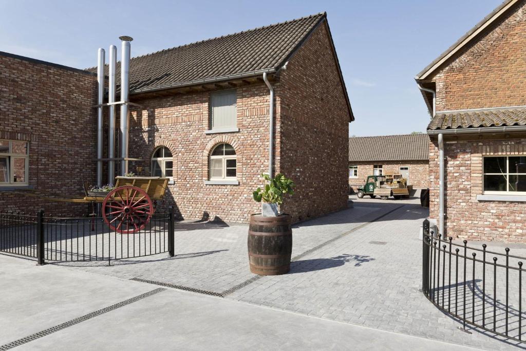 een bakstenen gebouw met een wiel erbuiten bij Craywinckelhof Streekbelevingscentrum in Lubbeek