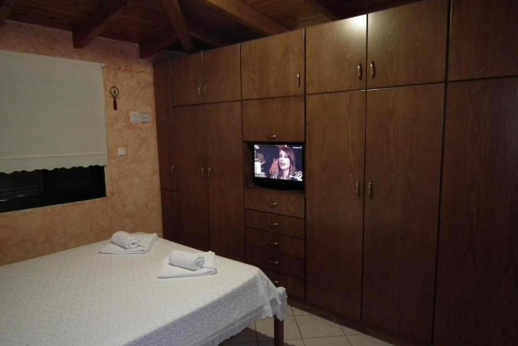 a bedroom with a bed and a tv and wooden cabinets at Gramvoussa Bay in Kissamos
