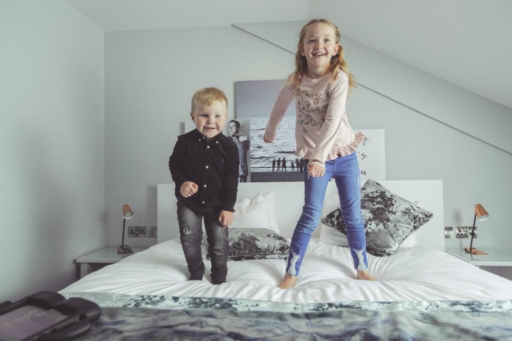 two children jumping on top of a bed at Formby Hall Golf Resort & Spa in Southport