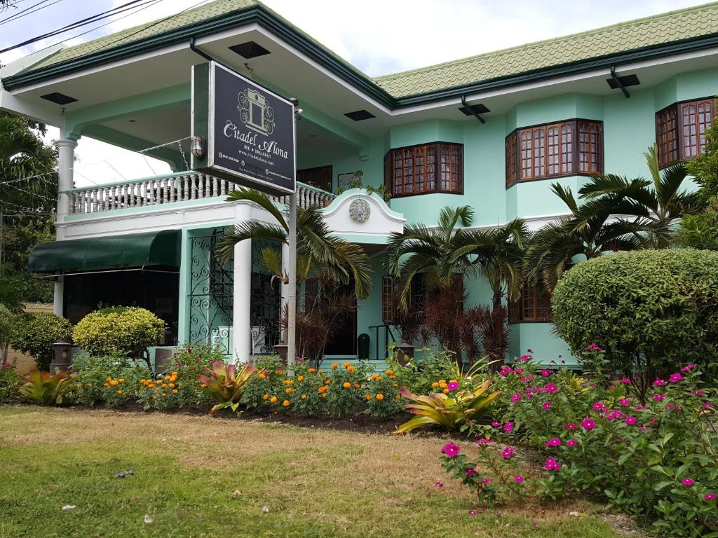 un edificio con un cartel delante de él con flores en Citadel Alona Inn, en Panglao